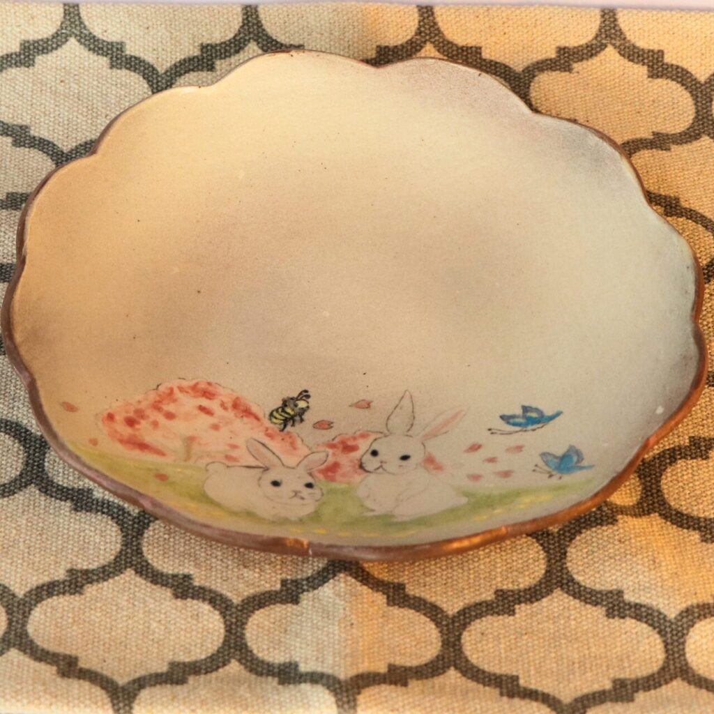 やす波窯のおしゃれ皿は通販の可愛い皿です。うさぎが二匹と蝶とミツバチさんが一緒に遊んでいます。